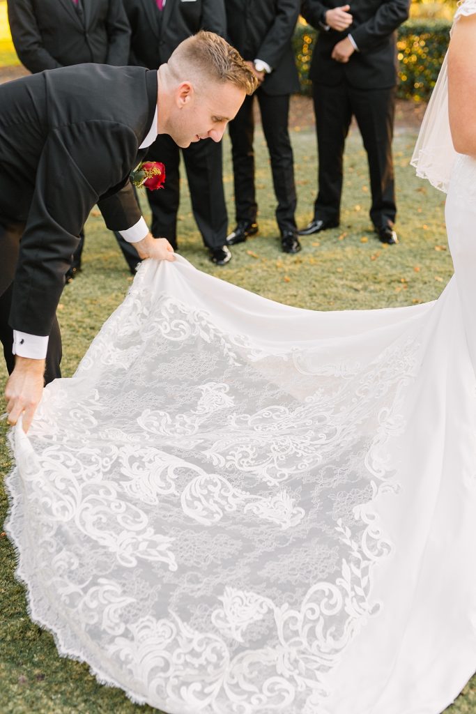 groom helping bride with dress train