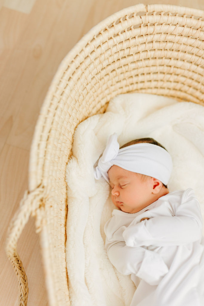 newborn baby in white gown in moses basket